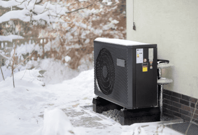 Air source heat pump against a wall working during winter in UK with snow around